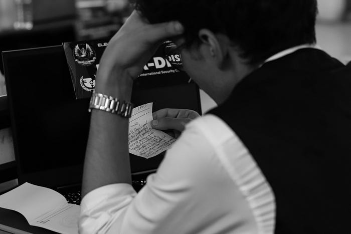 Man reading a handwritten note at his laptop – deep focus, business stress, or studying concept in black and white.