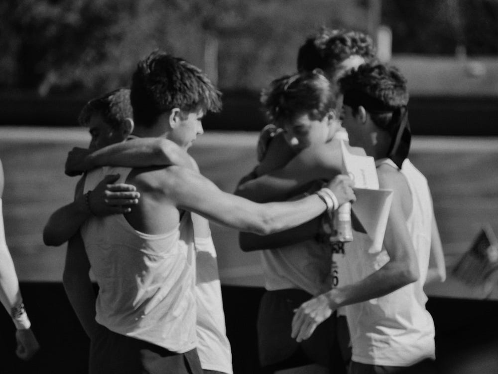 Black and white photo of athletes embracing in celebration – teamwork, sportsmanship, and emotional victory moment.