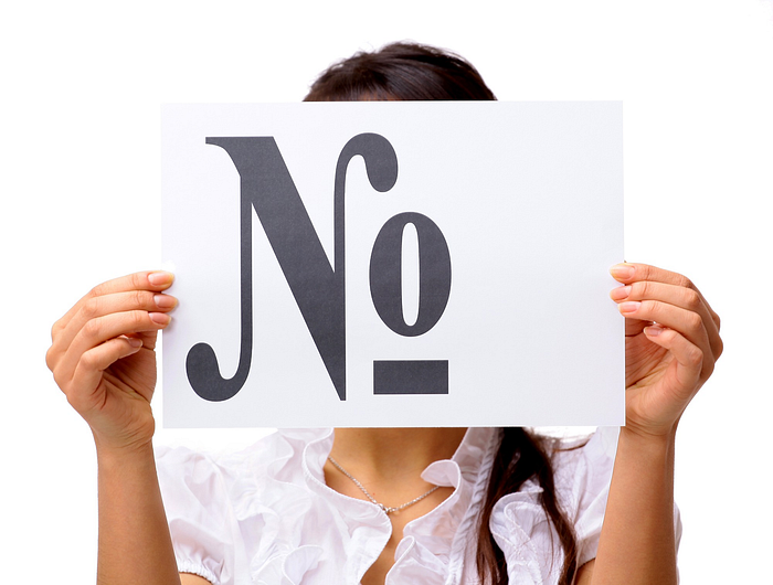 Woman holding a sign with the word ‘No’ – communication, refusal, and assertiveness concept.