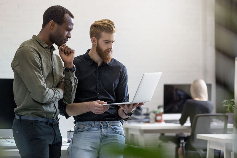 Two professionals discussing work on a laptop – business collaboration and teamwork in a modern office setting.