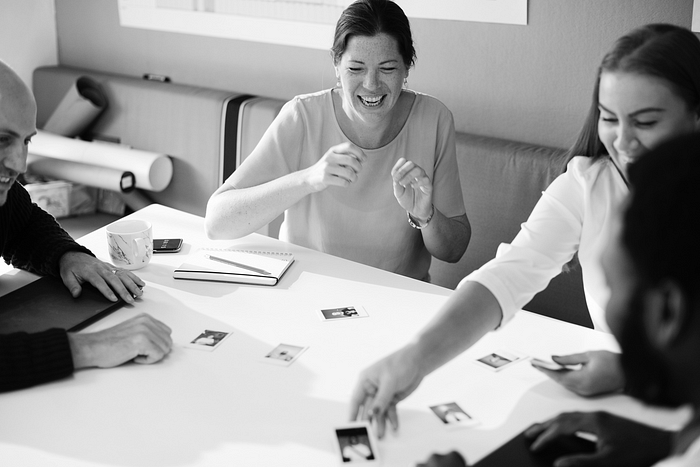 Black and white photo of a diverse group laughing and working together – teamwork, creativity, and collaboration in a professional setting.